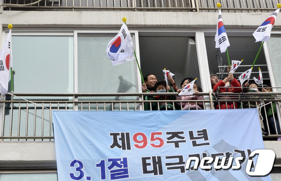 (서울=뉴스1) 최영호 기자 = 제95주년 3.1절을 앞두고 25일 오전 서울 성동구 사근동 중앙하이츠아파트에서 주민들과 아이들이 태극기를 흔들고 있다.성동구는 순국선열의 숭고한 …