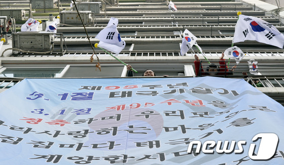 (서울=뉴스1) 최영호 기자 = 제95주년 3.1절을 앞두고 25일 오전 서울 성동구 사근동 중앙하이츠아파트에서 주민들과 아이들이 태극기를 흔들고 있다.성동구는 순국선열의 숭고한 …