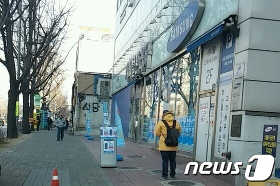본문 이미지 - 13일 서울 용산구의 한 삼성전자서비스센터 앞에 파손된 스마트폰 액정을 사기 위한 업자가 손님을 기다리고 있다.© News1 