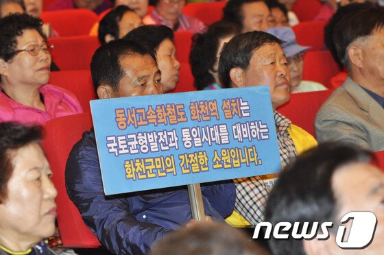 본문 이미지 - 14일 화천문화회관에서 동서고속화철도 화천역 설치를 위한 범 군민대책위원회가 출범했다. 한 군민이 화천역 설치 의지를 담은 피켓을 들고 앉아 있다. © News1   홍성우 기자