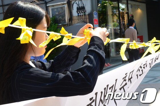 본문 이미지 - 세월호 여객선 침몰 사고 16일째인 1일 희생자들을 추모하기 위해 속초시민노동단체연대가 속초시내 S호텔 앞에 속초고성양양 합동 분향소를 마련한 가운데 한 시민이 정성스레 노란리본을 메달고 있다. 2014.5.1/뉴스1 © News1   엄용주 