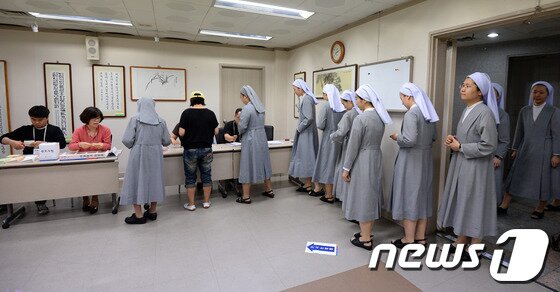 본문 이미지 - 전국동시지방선거일인 4일 오전 서울 중구 명동주민센터에 마련된 명동 제1투표소를 찾은 수녀들이 투표를 하기 위해 줄지어 서 있다. 2014.6.4/뉴스1 © News1   박지혜 기자