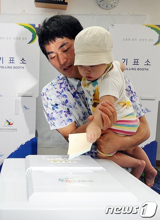 본문 이미지 - 6·4전국동시지방선거날인 4일 제주시 애월읍 광령1리사무소에 마련된 제6투표소에서 한 유권자가 자녀와 함께 투표를 하고 있다. 2014.6.4/뉴스1  © News1   이상민 기자