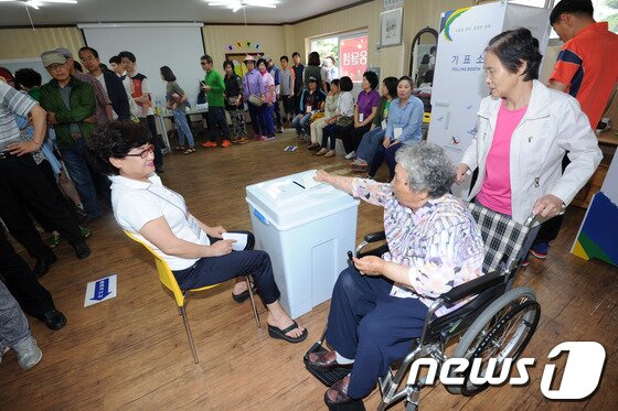 본문 이미지 - 6·4지방선거일인 4일 광주 풍암동 주은모아아파트 4투표소에는 시민들이 출을 서서 투표하고 있는가운데 고령의 한 할머니가 휠체어를 타고 투표하고 있다. 2014.6.4/뉴스1 © News1   김태성 기자