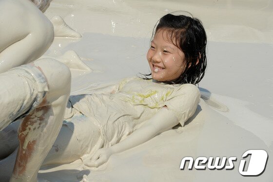 본문 이미지 - 27일 강원 동해시 망상해변에서 지역 천연광물인 화이트견운모를 이용한 축제가 열린 가운데 한 어린이가 화이트견운모 풀에 빠져 즐거워하고 있다. 이곳에서는 내달 3일까지 망상해변축제가 진행되며 현재까지 50여 만명의 피서객이 방문했다. 2014.7.27/뉴스1