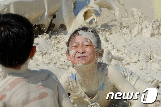 본문 이미지 - 27일 강원 동해시 망상해변에서 지역 천연광물인 화이트견운모를 이용한 축제가 열린 가운데 한 어린이가 화이트견운모 풀에 빠져 즐거워하고 있다. 이곳에서는 내달 3일까지 망상해변축제가 진행되며 현재까지 50여 만명의 피서객이 방문했다. 2014.7.27/뉴스1