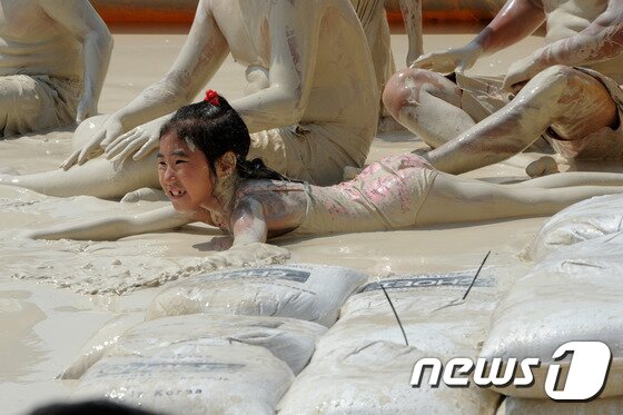 본문 이미지 - 27일 강원 동해시 망상해변에서 지역 천연광물인 화이트견운모를 이용한 축제가 열린 가운데 한 어린이가 화이트견운모 풀에 빠져 즐거워하고 있다. 이곳에서는 내달 3일까지 망상해변축제가 진행되며 현재까지 50여 만명의 피서객이 방문했다. 2014.7.27/뉴스1