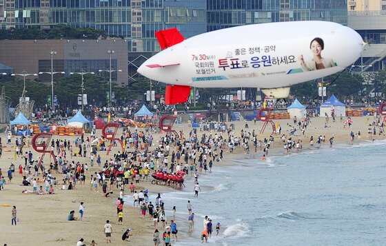 본문 이미지 - 27일 오후 부산 해운대해수욕장에 해운대구선거관리위원회가 7.30 국회의원 재보궐선거 투표독려를 위해 비행선을 날리며 홍보하고 있다. 2014.7.27/뉴스1 ⓒ News1 여주연