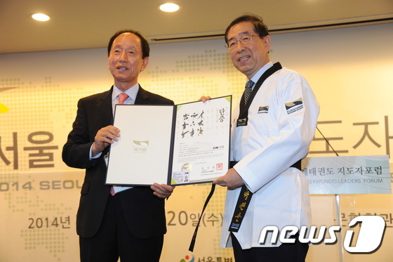 (서울=뉴스1) = 박원순 서울시장이 19일 오전 서울 종로구 세종문화회관 세종홀에서 열린 '세계태권도지도자 포럼 개회식'에서 국기원 정만순 원장으로부터 명예단증(7단)과 태권도복 …
