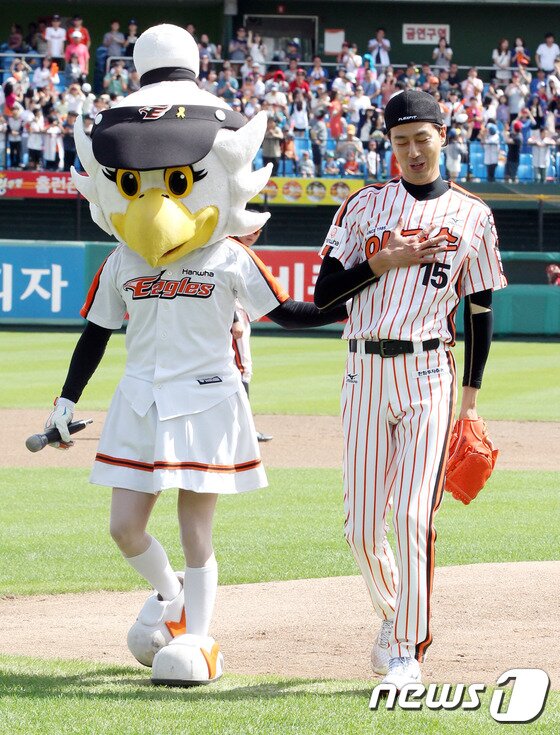 본문 이미지 - 배우 조인성이 시구를 끝낸 뒤 한화 마스코트 비니의 에스코트를 받고 마운드에서 내려오고 있다. 시구를 잘 끝낼 수 있어 다행이라는 듯 가슴에 손을 얹고 안도의 한숨을 내쉬고 있다.  ⓒ News1 스포츠 /  한화 이글스 제공