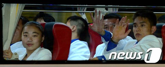 본문 이미지 - 제17회 인천아시아경기대회에 참여하는 북한 선수단이 평양발 고려항공을 통해 16일 오후 인천국제공항을 통해 입국한 뒤 선수촌으로 향하는 버스에 탑승해 남북공동응원단을 향해 손을 흔들고 있다. 2014.9.16/뉴스1 ⓒ News1 박정호 기자