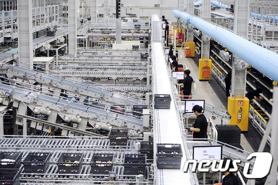 본문 이미지 - 보정센터 피킹 담당 직원들이 컨베이어 벨트로 옮겨지는 박스에 물건을 담고 있다. 고객에게 배송될 박스가 작업자를 찾아가는 방식으로 주문상품이 빠지는 결품률을 기존 3%대에서 0.2%로 대폭 낮췄다.ⓒ News1