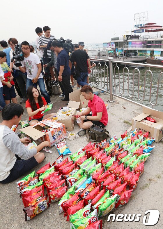 본문 이미지 - 제과업계의 과자 과대포장에 항의하는 대학생들이 28일 오후 서울 잠실한강공원 선착장에서 과자 150개를 이어 붙여 '과자 뗏목'을 만들고 있다. 2014.9.28/뉴스1 ⓒ News1 오대일 기자
