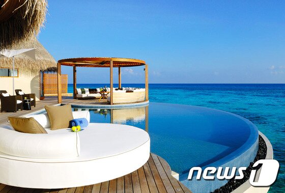 본문 이미지 - 거실을 나서면 나무데크 위에 흰색의 데이베드가 놓여 있고 그 아래로는 부채꼴 모양의 인피니티 수영장이 파란 물을 담고 있다. 사진 제공/ 허니문리조트 ⓒ News1