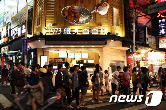 본문 이미지 - 타이중 펑자 야시장을 찾은 현지인들이 '닭튀김'으로 유명한 식당을 지나가고 있다. ⓒ News1 