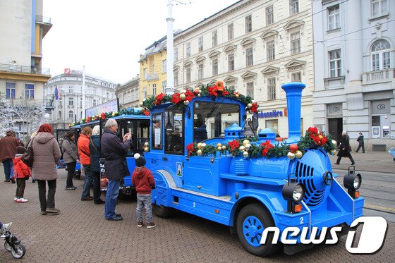 본문 이미지 - 자그레브 반 옐라치치 광장에 마련된 꼬마 특급열차. 이 열차는 아이들을 태우고 광장을 지나 시내 한 바퀴를 돌아다닌다. 열차에 올라탄 아이의 모습을 담기 위해 기념촬영을 하는 가족들. 뉴스1트래블 ⓒ News1 travel 조용식 기자