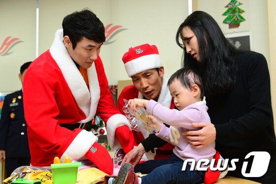 본문 이미지 - 24일 오전 크리스마스 이브를 맞아 서울 영등포구 한강성심병원에서 열린 '몸짱 소방관 달력 수익금, 화상환자에게 전하는 희망' 행사에서 산타로 변신한 몸짱 소방관들이 열탕화상을 입고 치료 중인 이하윤(2세) 양에게 장난감을 전달하고 있다. 2015.12.24/뉴스1 ⓒ News1 임세영 기자