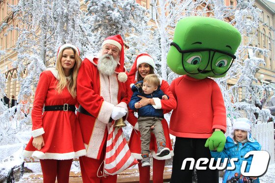 본문 이미지 - 미녀 산타의 품에 안겨 기념촬영을 하고 있는 꼬마의 무표정이 재미있기만 하다. 자그레브 크리스마스마켓에서 산타와 미녀 산타가 등장해 마켓을 찾은 시민들과 기념촬영을 하고 있다. 2015.12.6/뉴스1트래블 ⓒ News1 조용식 기자