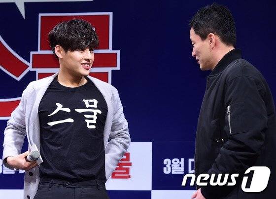 본문 이미지 - 배우 강하늘이 12일 오전 서울 강남 신사동 압구정 CGV에서 열린 영화 ‘스물’ 제작보고회에 앞에는 "스물", 뒤에는 "경재"가 적힌 티셔츠를 입고 이병헌 감독(오른쪽)에게 자랑을 하고 있다. ⓒ News1 스포츠 / 권현진 기자