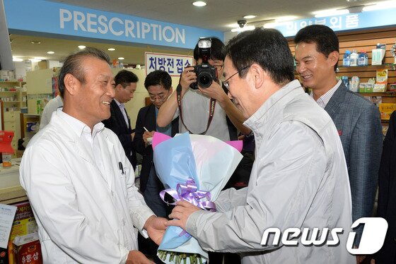 본문 이미지 - 19일 부산지역 첫 확진 환자가 지난 6일 부산의료원에 격리되기 전에 들렀던 부산시 사하구 대선약국을 찾은 서병수 부산시장이 약국 약사에게 꽃다발을 전달하고 있다. 이날 서 시장은 최초 확진환자가 다녀갔다는 소식이 알려져 심적·물적으로 고생한 임홍섭 내과의원, 대선약국과 사하 목촌돼지국밥집을 찾아 초기 적절한 대응으로 메르스 확산방지에 큰 역할을 해준 것에 대하여 격려했다.2015.6.19/뉴스1 ⓒ News1 이승배 기자