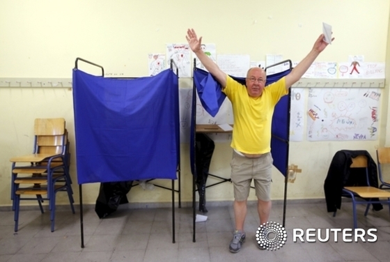 Man raises his arms as he leaves a polling booth before casting his ballot during a referendum vote in Athens, Greece