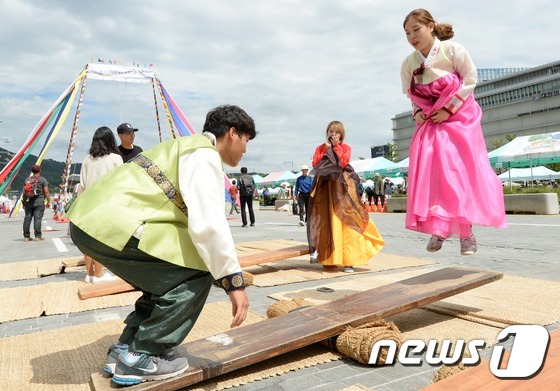 (서울=뉴스1) 손형주 기자 = 6일 오후 서울 세종대로 보행전용거리에서 열린 추석맞이 전통문화 대축제에서 시민들이 널뛰기 체험을 하고 있다. 이번 축제에는 줄타기와 대형그네 등 …