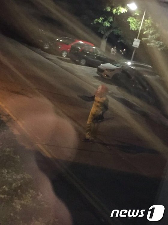 본문 이미지 - 브루넬 대학교 앞에 전기톱을 든 광대복장 남성이 행인을 위협하고 있다.[출처=트위터]ⓒ News1