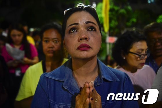 본문 이미지 - 태국 시민들이 국왕이 입원한 병원 앞에 모여들어 그의 사진을 들고 쾌유를 바라는 기도를 했다.ⓒ AFP=뉴스1