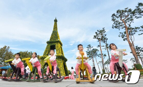 본문 이미지 - '유성 국화전시회'를 찾은 지역의 어린이집 아이들이 국화로 만든 에펠탑을 배경으로 목마를 타며 가을을 정취를 느끼고 있다. ⓒ News1 주기철 기자