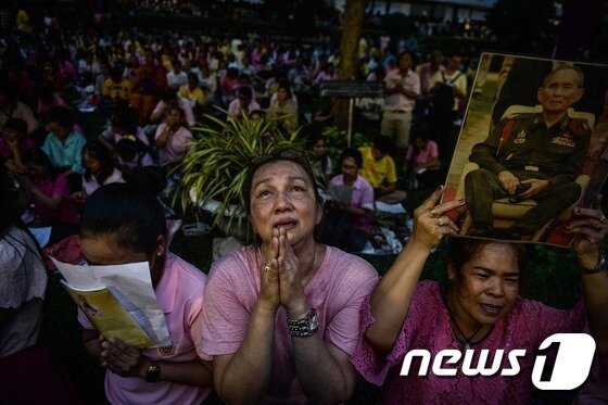 본문 이미지 - 13일(현지시간) 푸미폰 아둔야뎃(88) 태국 국왕이 숨졌다는 소식 전해지자 방콕 주민들이 기도를 올리고 있다. 70년간 태국을 통치해온 그는 특유의 검소함과 많은 봉사 등으로 '살아있는 신(神)'이라 불리며 태국인들에 존경과 사랑을 한몸에 받았다.ⓒ AFP=뉴스1