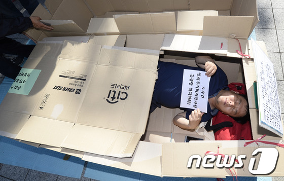 (서울=뉴스1) 허예슬 인턴기자 = 3일 오전 서울 종로구 보신각 앞에서 열린 '세계 주거의 날' 기념행사에서 한 참가자가 홈리스들을 위한 박스집만들기 체험을 하며 피켓을 들고 있 …