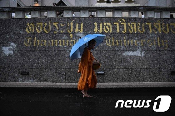 본문 이미지 - 한 승려가 6일(현지시간) 탐마삿대 학살 40주년 기념식이 끝난 뒤 학교 옆을 지나가고 있다. ⓒ AFP=뉴스1