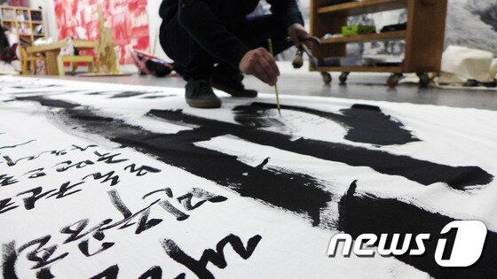 본문 이미지 - 지난해11월 임옥상 화백이 경기도 고양시에 위치한 자신의 작업실에서  '백만백성' 퍼포먼스를 위해 흰 천에 붓글씨를 쓰고 있다. ⓒ News1