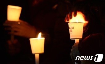 박근혜 대통령 퇴진을 위한 온오프라인 촛불시위가 이어지고 있는 가운데 28일 서울 중구 서울파이낸스센터 앞에서 열린 박근혜 퇴진을 위한 촛불집회에서 한 참석자가 촛불에 언 손을 녹이고 있다. 2016.11.28/뉴스1 ⓒ News1 오대일 기자