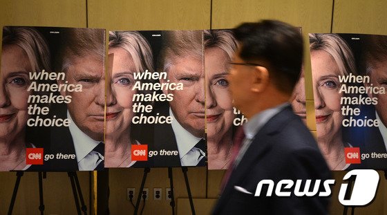 본문 이미지 - 제45대 미국 대통령 선거일인 2016년 11월9일&#40;한국시간&#41; 오전 서울 종로구 포시즌호텔에서 열린 2016 미국 대선 시청행사에서 한 참가자가 대선 후보인 힐러리 클린턴과 도널드 트럼프 후보의 사진 앞을 지나고 있다. 2016.11.9/뉴스1 ⓒ News1 구윤성 기자