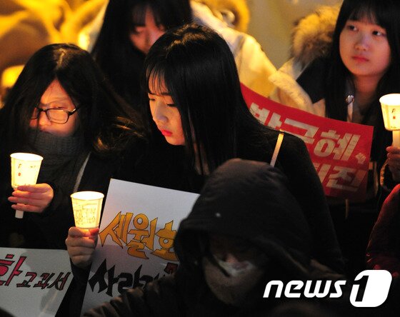 본문 이미지 - 17일 오후 울산 남구 삼산동 롯데백화점 광장에서 '박근혜 대통령 즉각 퇴진 및 황교안 대통령 권한대행 퇴진'을 요구하는 촛불집회가 열린 가운데 한 여학생이 세월호 관련 피켓을 들고 촛불을 밝히고 있다. 2016.12.17/뉴스1 ⓒ News1 이윤기 기자