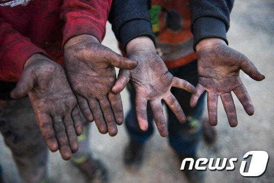본문 이미지 - 불타는 유전 근처에 사는 아이들의 손이 검댕으로 까매져 있다. ⓒ AFP=뉴스1