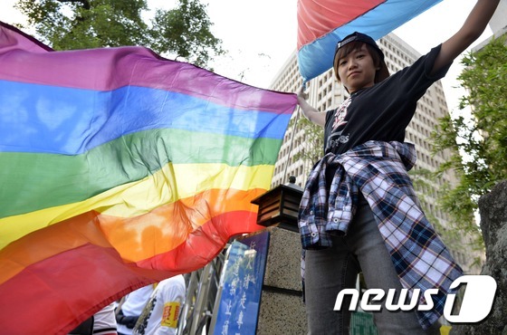 17일(현지시간) 대만 타이페이 입법원(국회) 앞에서 동성 결혼 지지자가 무지개빛 깃발을 들고 서 있다.  © AFP=뉴스1