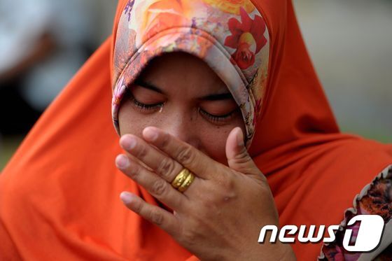 본문 이미지 - 26일(현지시간) 인도네시아 아체주에 있는 한 공동묘지에서 한 여성이 기도를 하다 도중에 눈물을 보였다 ⓒ AFP=뉴스1