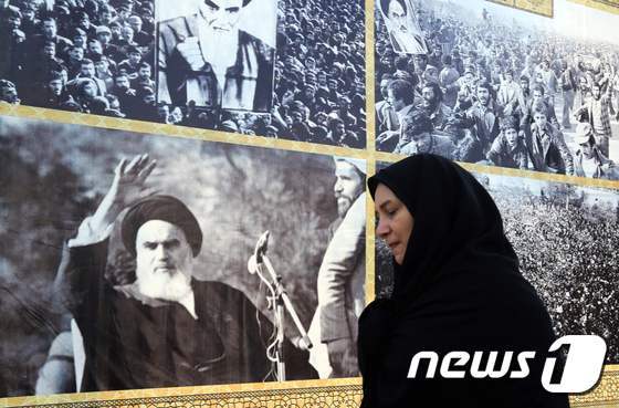 본문 이미지 - 한 이란 여성이 테헤란에서 이란 이슬람 혁명의 아버지 아야톨라 루홀라 호메이니(1900∼1989)의 사진이 붙어 있는 입간판 앞을 지나고 있다. ⓒ AFP=뉴스1 ⓒ News1 최종일 기자