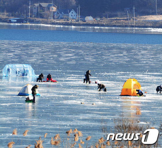 (춘천=뉴스1) 정진욱 기자 = 입춘을 앞둔 2일 강과 호수의 얼음이 녹고 있는 가운데 강원도 춘천시 사북면 춘천호에서 관광객들이 얼음 낚시를 하고 있다. 입구에 걸려있는 '얼음이 …