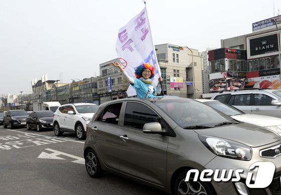 (서울=뉴스1) 안은나 기자 = 제20대 국회의원 선거를 하루 앞둔 12일 오후 서울 강서구 발산역 인근에서 열린 한 후보의 지원 유세에서 한 시민이 차를 타고 거리를 돌며 투표 …