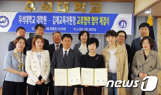 본문 이미지 - 26일 우석대학교 본관 대회의실에서 열린 우석대 대학원과 김제교육지원청의 교류협력 협약 체결식에 참석한 관계자들이 기념사진을 촬영하고 있다. 양 기관은 청소년들의 올바른 자아관 형성을 위한 프로그램 개발 및 운영을 위해 이날 협약식을 가졌다. 우석대 대학원 석사과정에 재학 중인 샤이니 키와 스타일리스타 서수경씨도 이번 프로그램에 참여한다.(우석대학교 제공)2016.04.26./뉴스1 ⓒ News1 박효익 기자