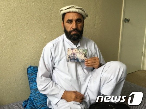 본문 이미지 - 모하메드 굴랍이 2005년 마커스 루트렐을 구했을 당시의 사진을 들어 보이고 있다.(Newsweek) ⓒ News1