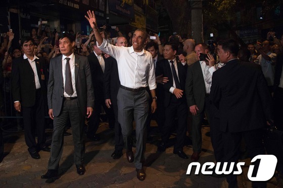 베트남을 방문 중인 버락 오바마 미국 대통령이 23일 (현지시간) 하노이 분짜 흐엉 리엔 식당에서 CNN의 셰프 안소니 부르댕과 함께 저녁을 먹은뒤 시민들에게 손을 흔들고 있다.© AFP=뉴스1 