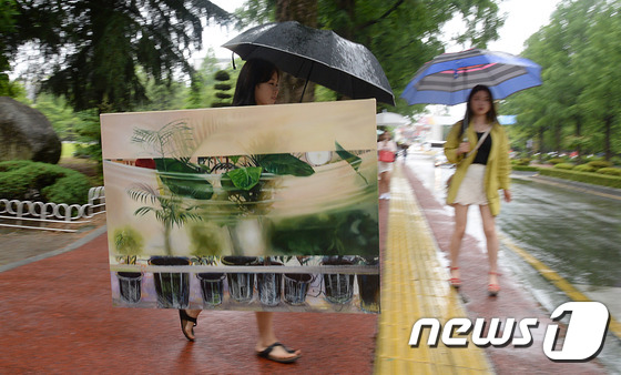 (대전ㆍ충남=뉴스1) 주기철 기자 = 초여름비가 내린 24일 오전 대전 한남대학교 캠퍼스에서 서양화과 한 학생이 우산을 들고 과제물로 그린 그림이 비에 젖지 않도록 조심히 걷고 있 …
