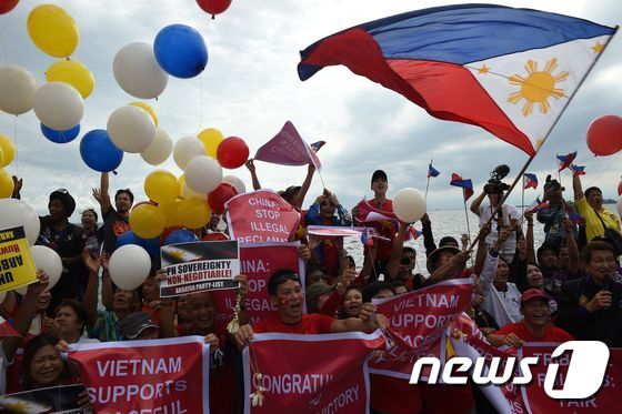 본문 이미지 - 필리핀과 베트남 시민 운동가들이 12일 마닐라에서 필리핀 측에 우호적인 네덜란드 헤이그 상설중재재판소(PCA) 판결을 기대하며 국기를 흔들고 있다. AFP=뉴스1
