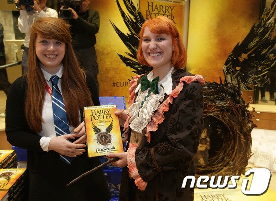 본문 이미지 - 영국 런던의 한 서점가에서 31일(현지시간) '해리포터와 저주받은 아이' 대본집 첫 구매자가 되기 위해 수시간 줄을 서서 기다린 한 여성이 기념사진을 찍고 있다. ⓒ AFP=뉴스1