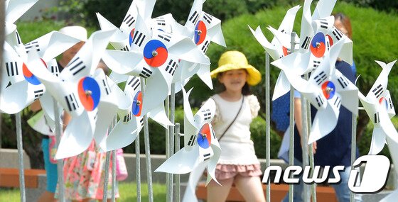 본문 이미지 - 제 71주년 광복절을 사흘 앞둔 12일 서울 종로구 대한민국역사박물관 앞에서 시민들이 태극기 바람개비 앞을 지나가고 있다. 2016.8.12/뉴스1 ⓒ News1 황기선 기자