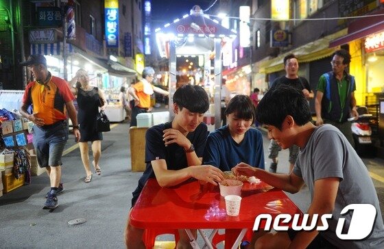 본문 이미지 - 부산 초량전통시장 야시장 매대 가운데 마련된 테이블에서 관광객들이 음식을 먹고 있다. ⓒ News1 여주연 기자